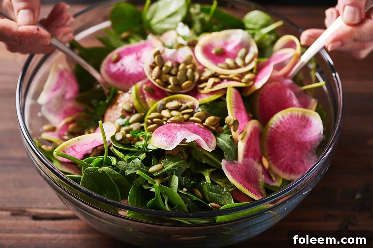 Fall Vegetable and Farro Salad topped with slices of watermelon radishes and pepitos.