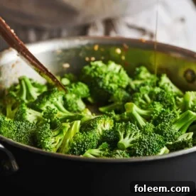 Broccoli cooking in pan on stove.