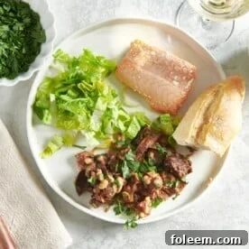 Fish, salad, bread, and Mushroom, Tomato and White Bean Ragout on a white plate.