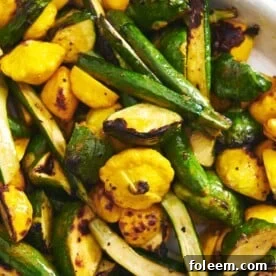 Roasted carrots, squash, parsnips, and other vegetables on white plate.