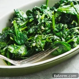Sauteed spinach in green dish with fork.
