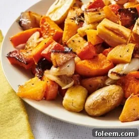 Roasted carrots, squash, parsnips, and other vegetables on white plate.