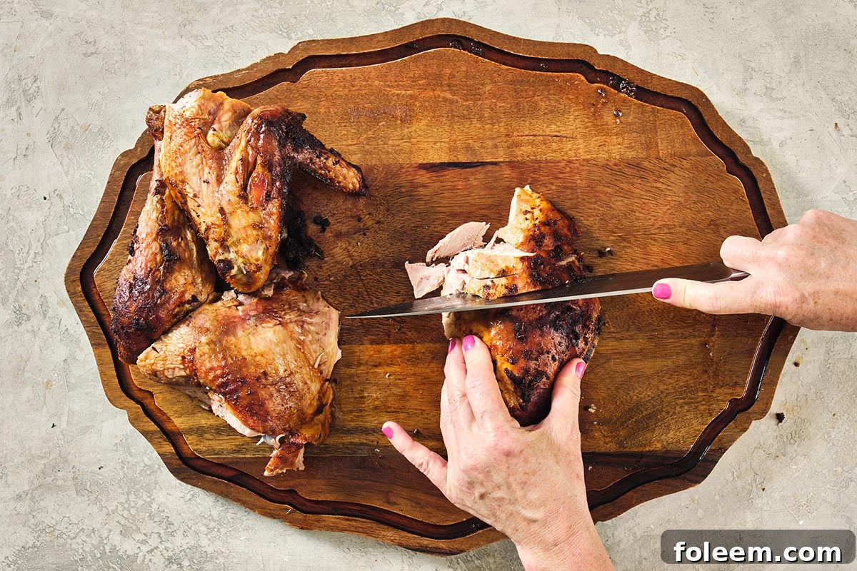 Woman cutting up roast Cajun turkey on a wooden cutting board.