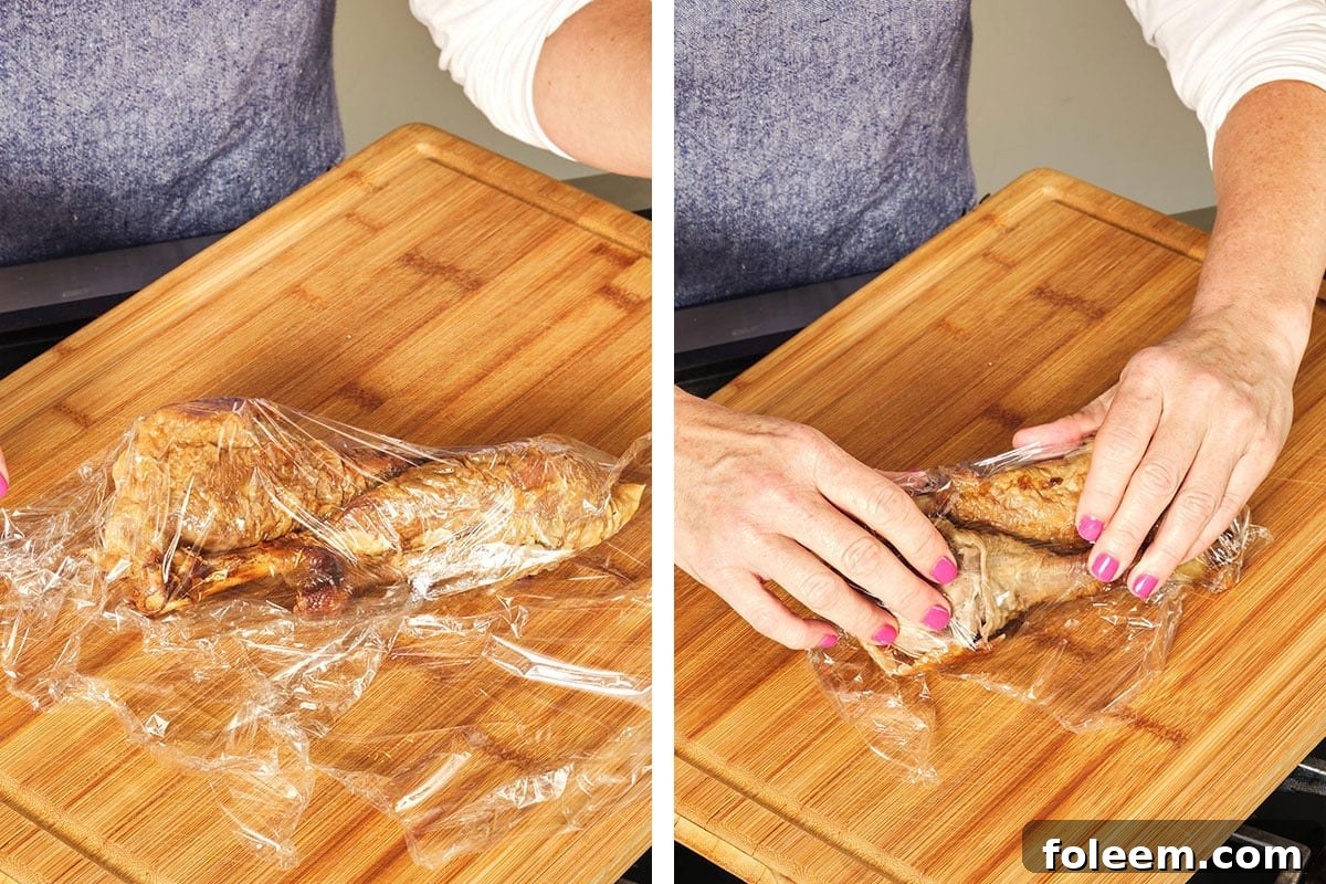 Woman wrapping turkey drumsticks in plastic wrap.