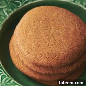 Homemade gingersnap cookies stacked on green plate.
