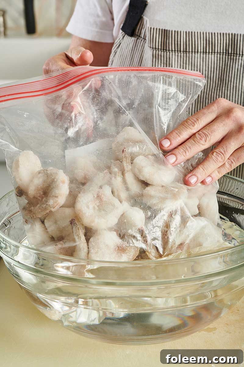 Hands placing a bag of frozen shrimp into a bowl of water.