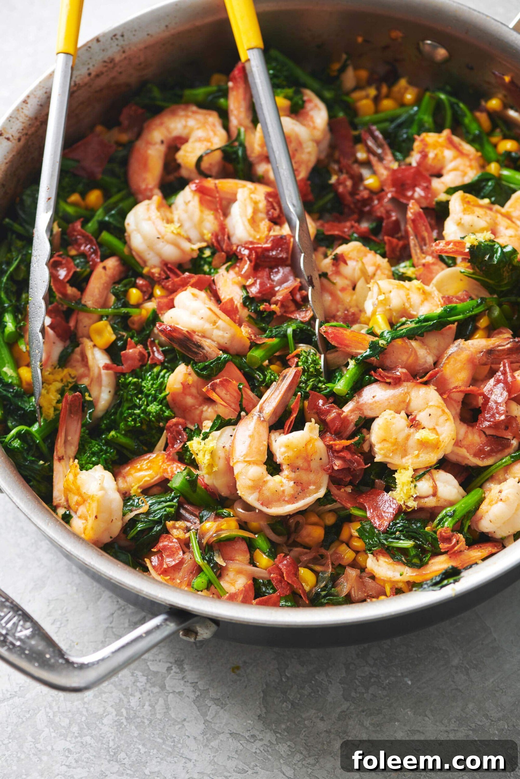 Tongs grabbing Sauteed Shrimp with Vegetables.