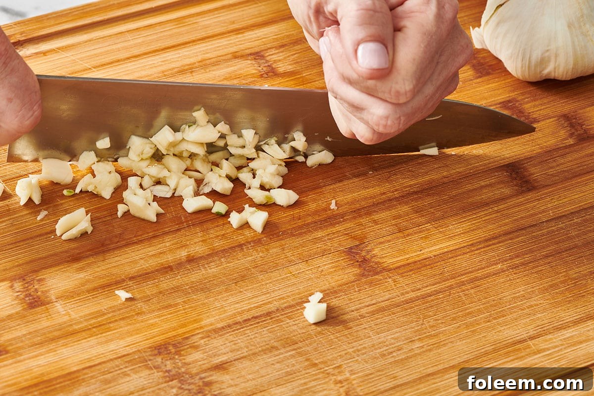 Chopping fresh garlic with chef knife.