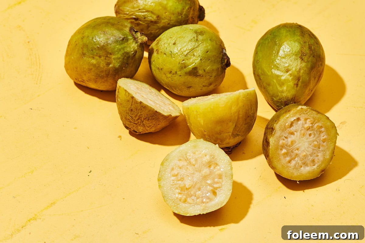 Whole and sliced guava on yellow table.