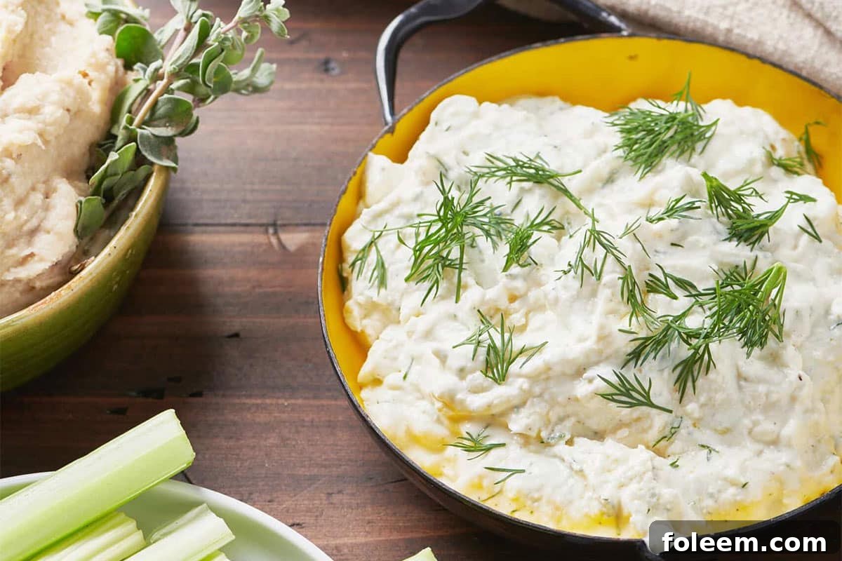 Bowl of Feta Yogurt Dip with fresh dill on a wooden table.