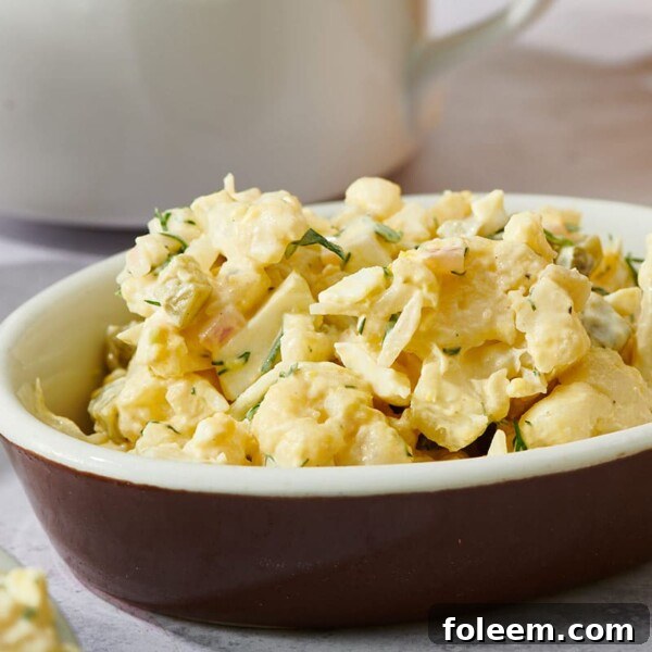 Brown dish with cauliflower potato salad on table.