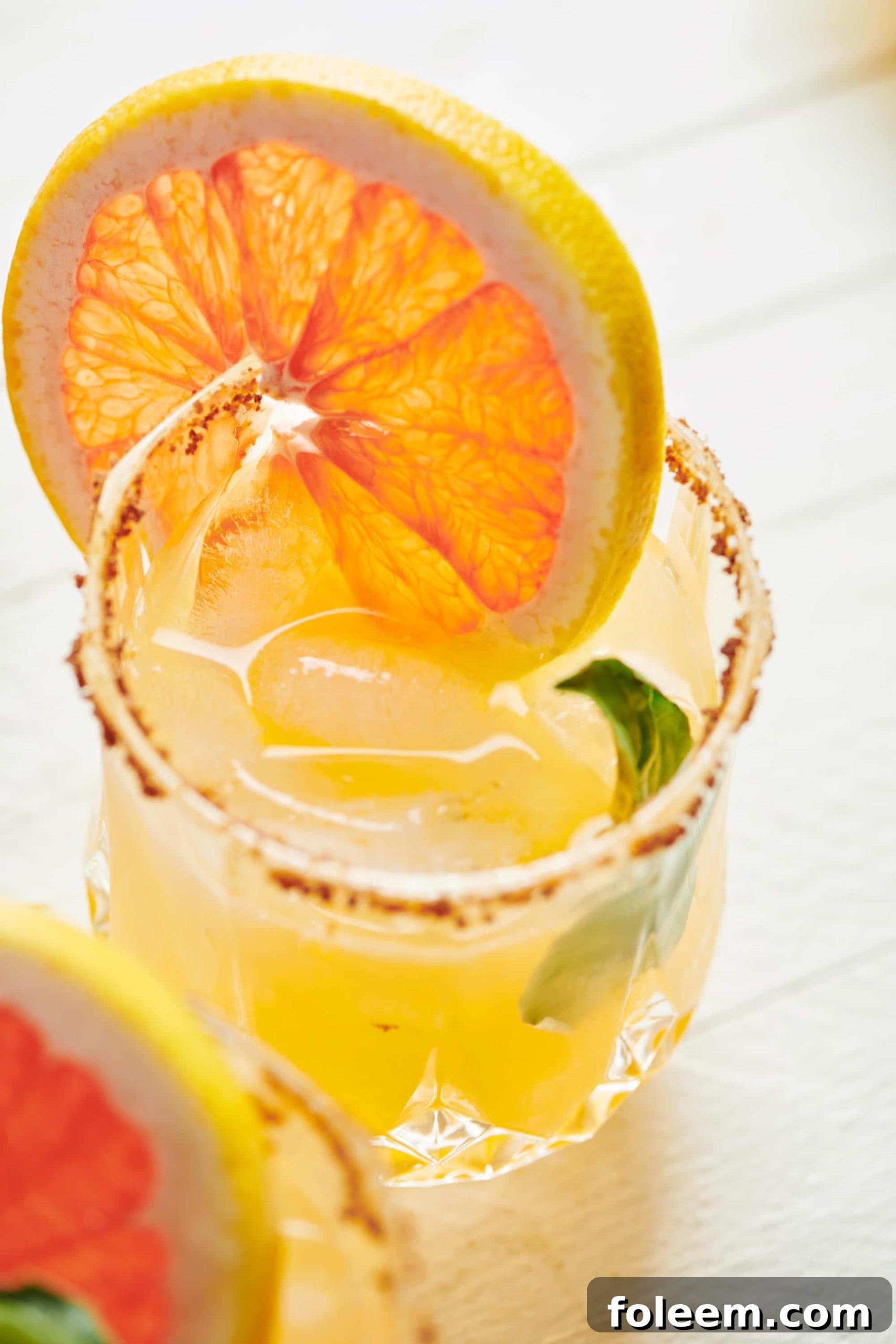 Pomelo and yuzu paloma cocktail in rocks glass with citrus garnish.
