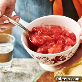 Woman scooping strawberry topping from a small bowl.