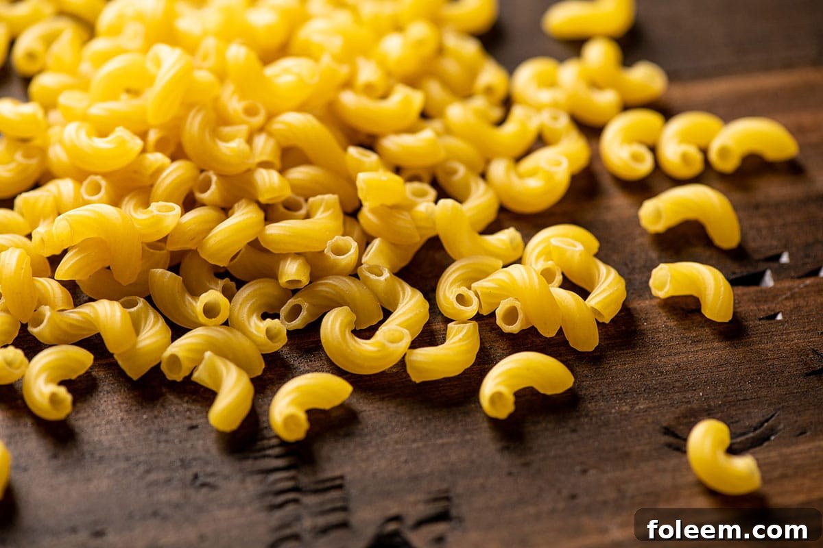 Dried elbow macaroni pasta on wood board