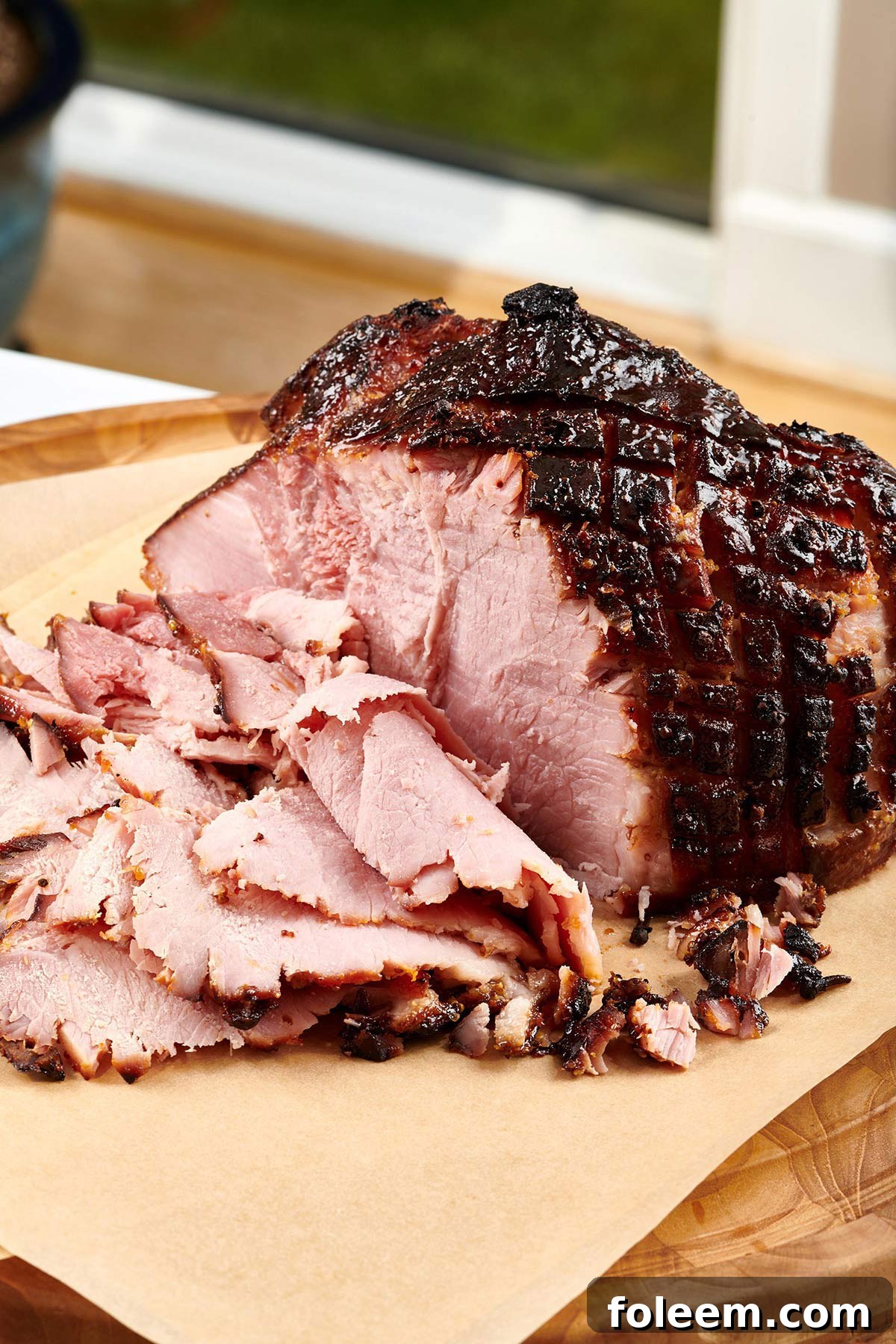 Old-fashioned baked ham partially sliced on cutting board.