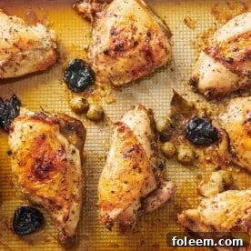Chicken Marbella on a lined baking sheet.