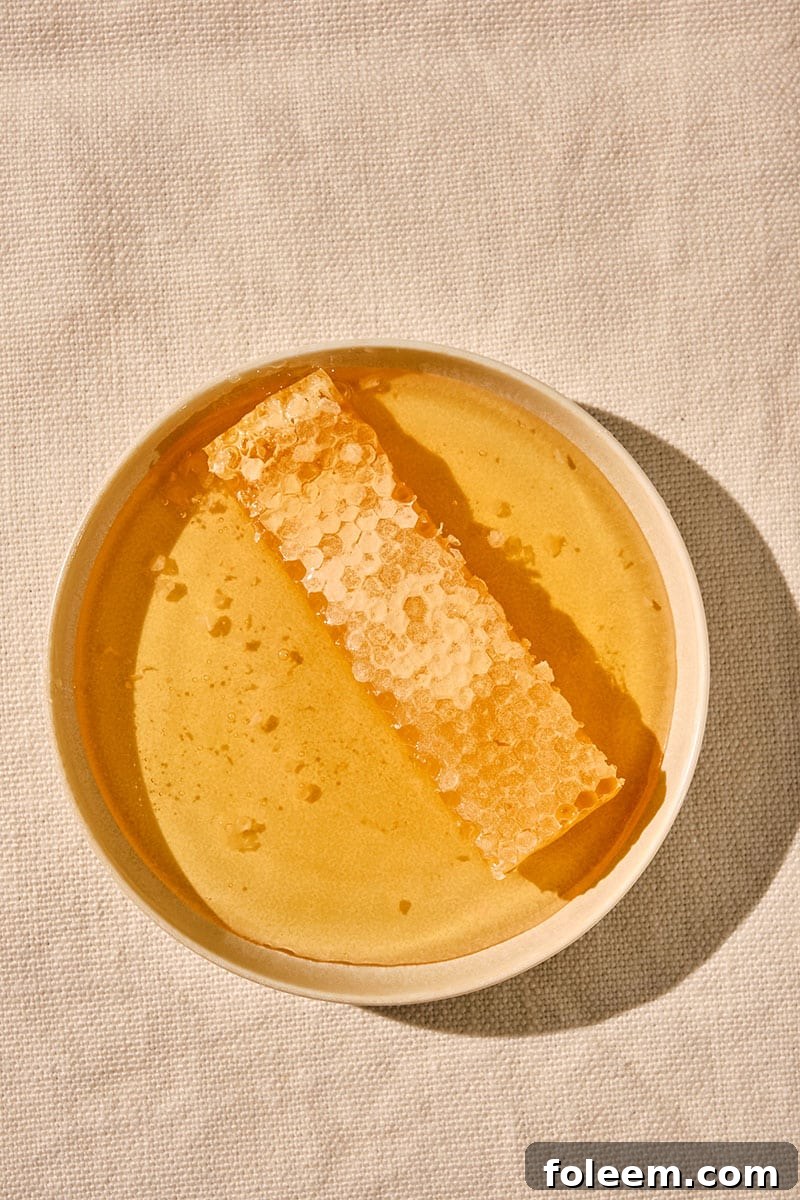 Fresh honeycomb in bowl of honey on wood table.