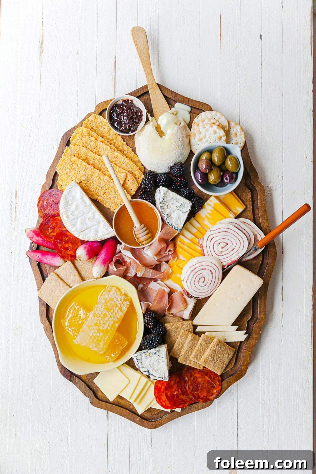 Platter on table filled with cheeses, meats, honeycomb and other graze board delicacies.