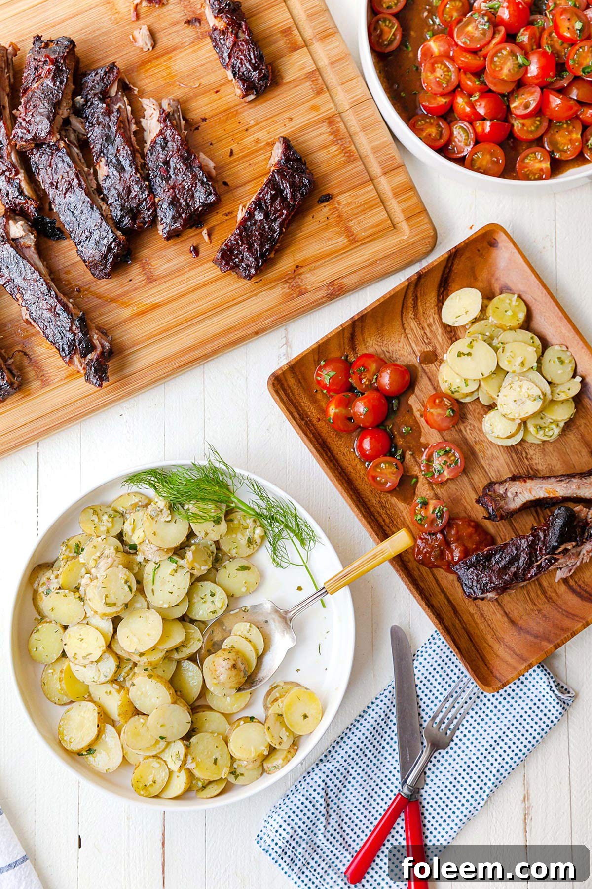 Wood table with Cherry Tomato Salad, French potato salad, and Cajun ribs.