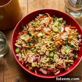Vegetable and Brown Rice Salad with Honey Lemon Dressing in red bowl on table.