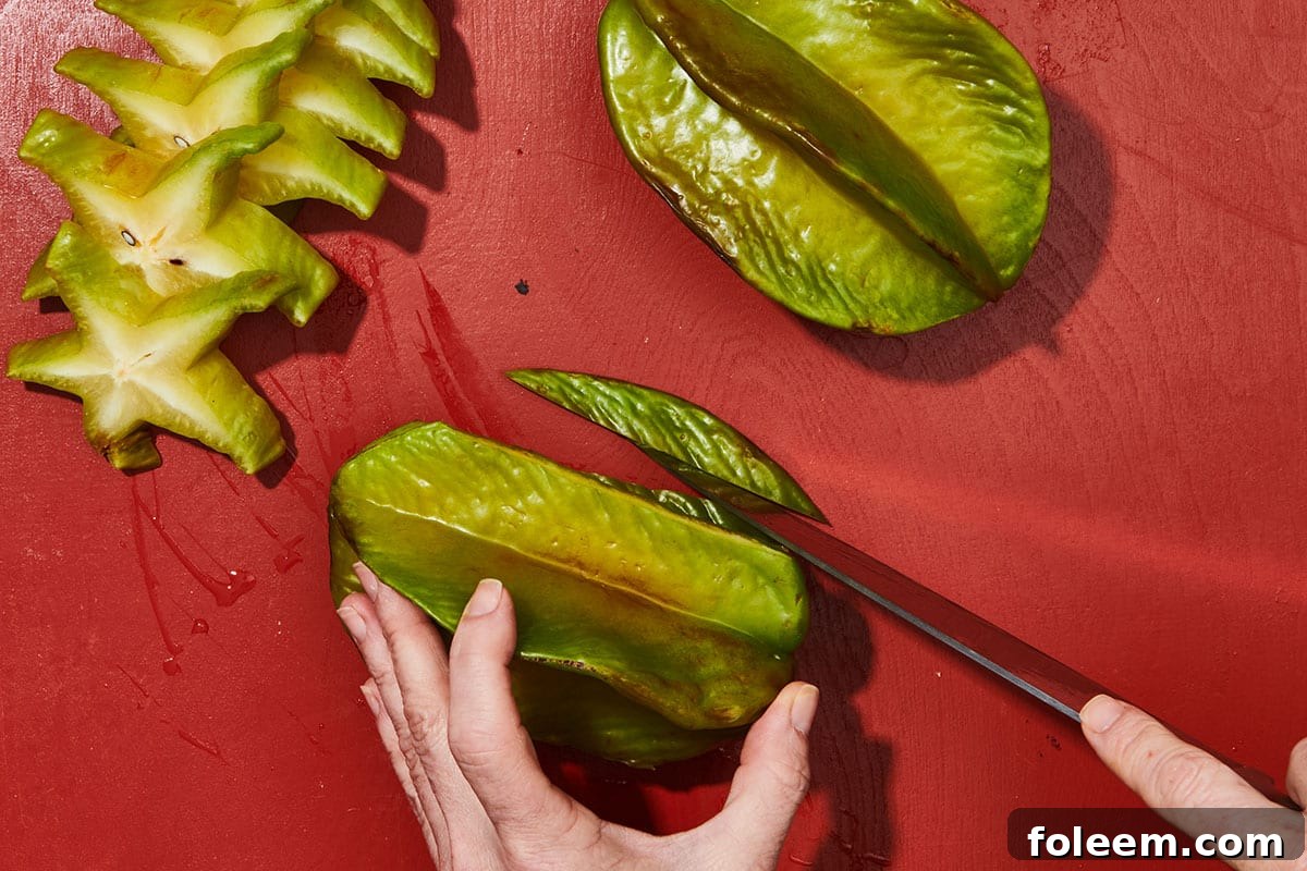 Woman slicing tips off starfruit ridge.