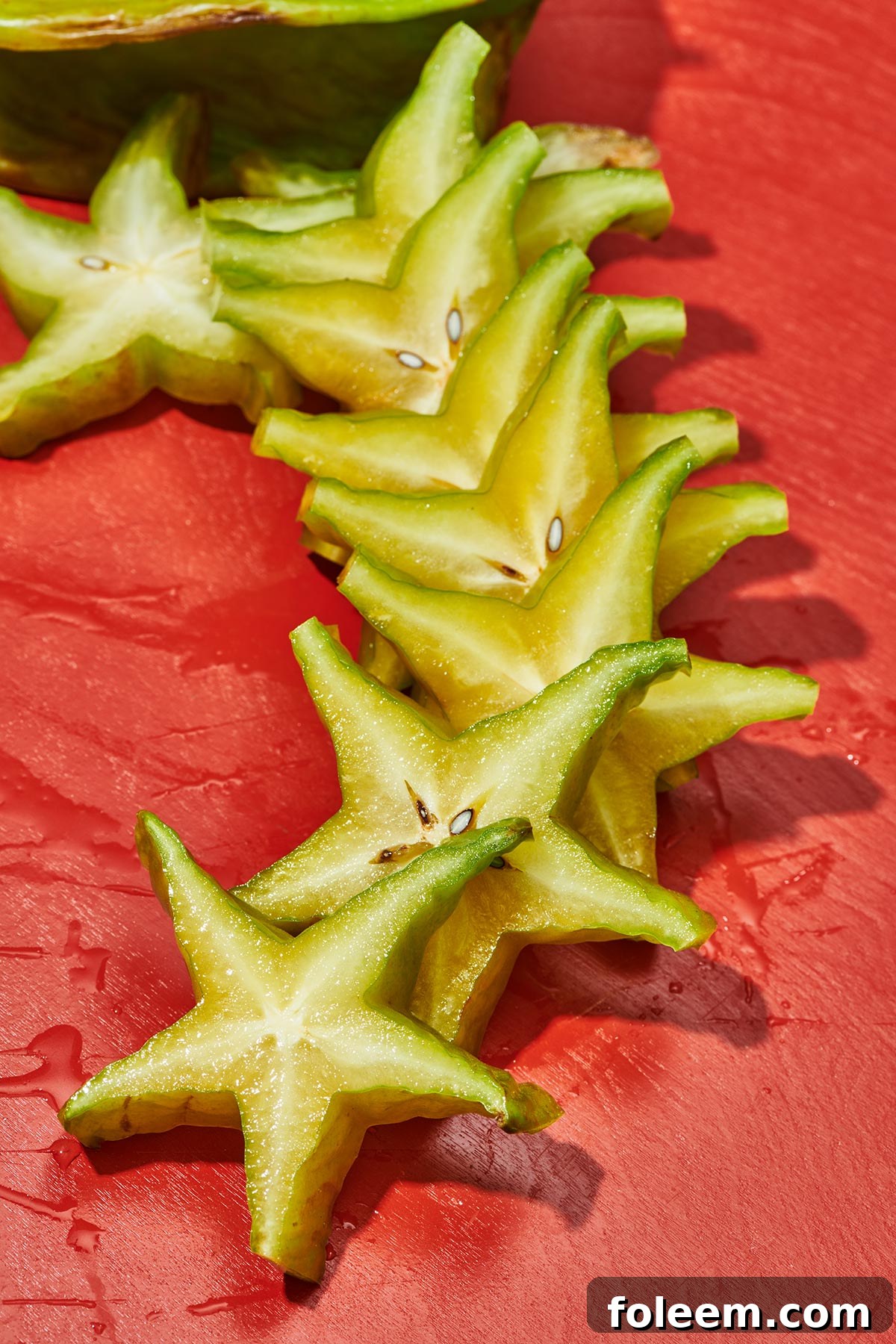 Slices of fresh starfruit fanned out on red table.