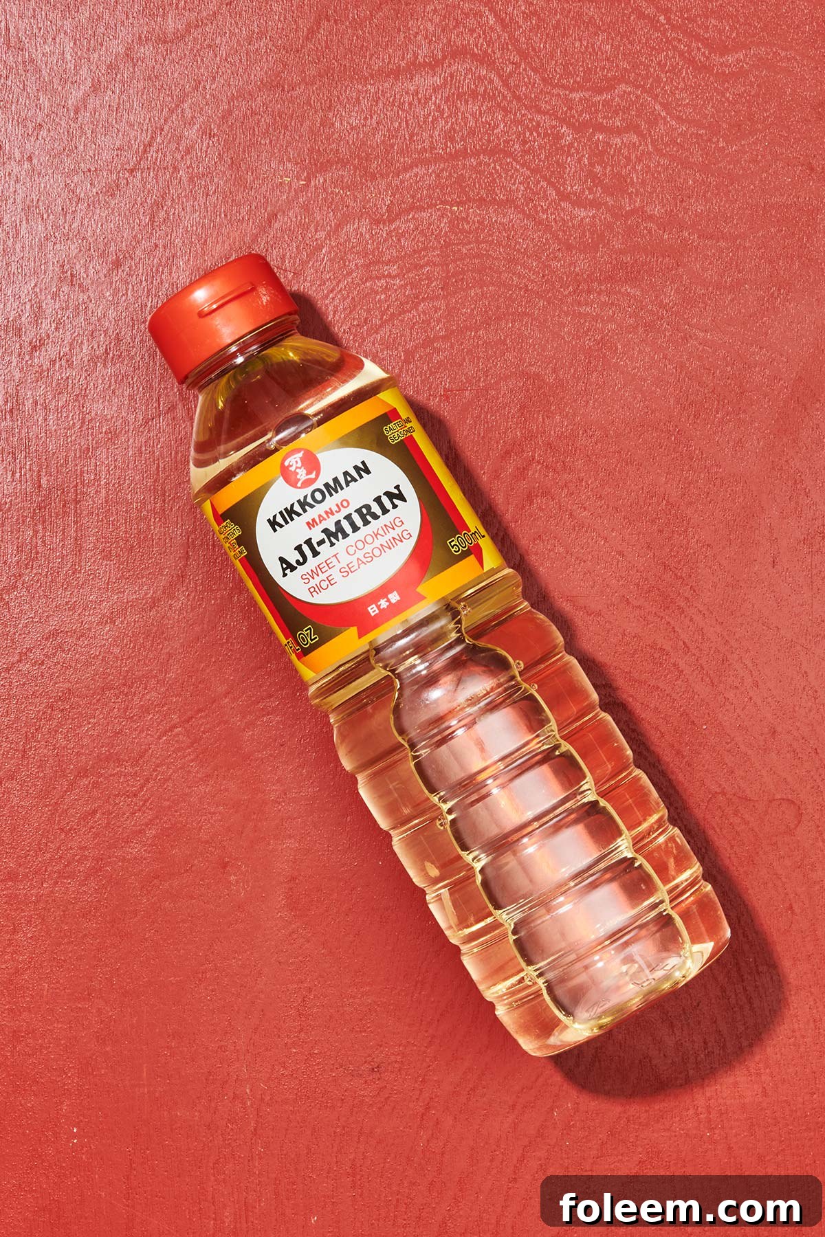 Bottle of Kikkoman mirin on red table.