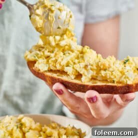 Woman spooning egg salad on bread.