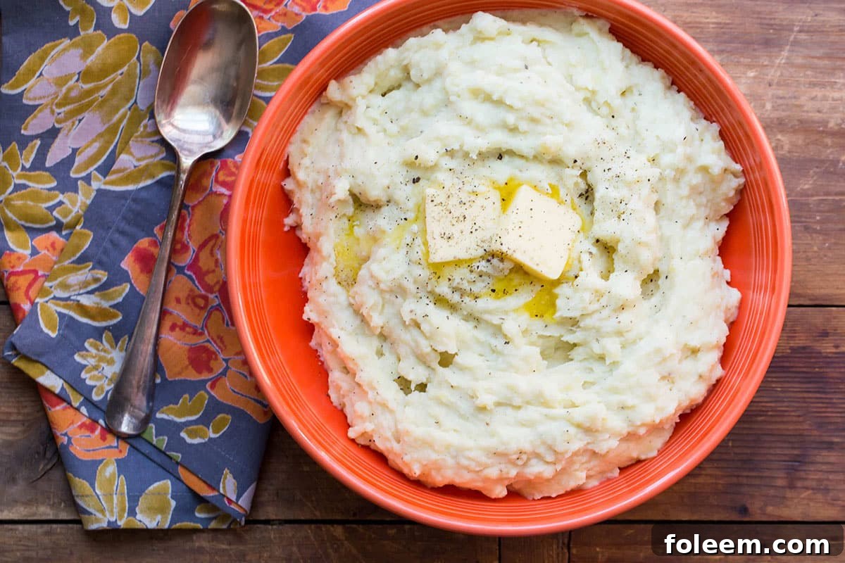 Bowl of Cheesy Mashed Potatoes topped with butter.