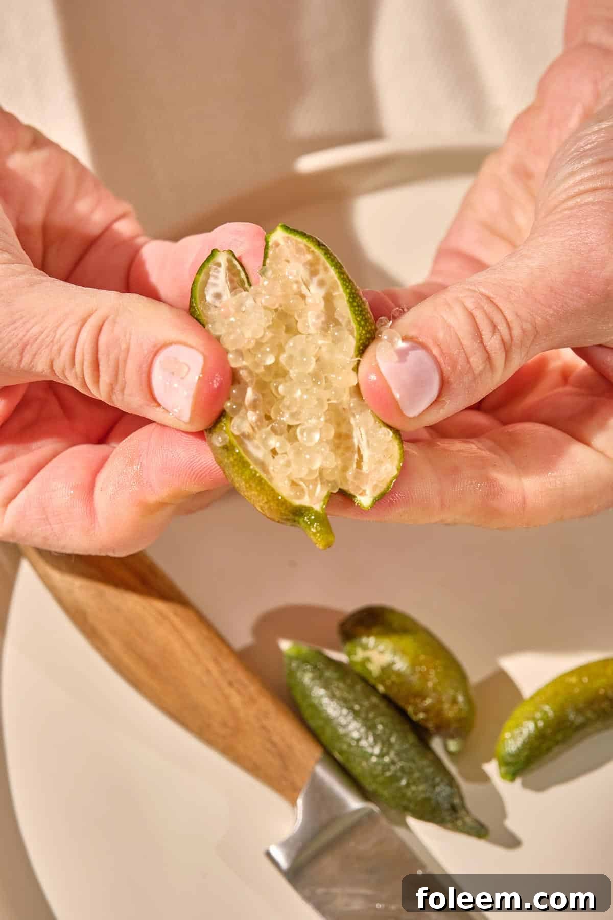 Woman holding open sliced finger lime.