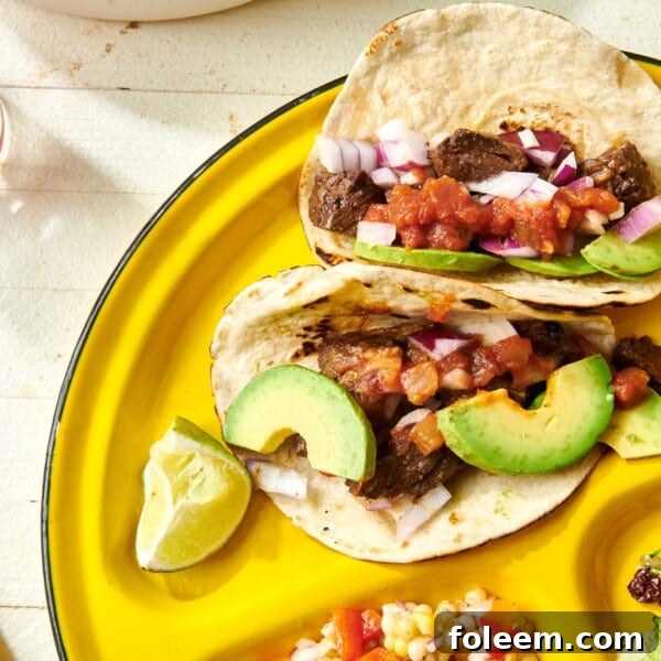 Steak Street Tacos on yellow plate with avocado and other toppings.