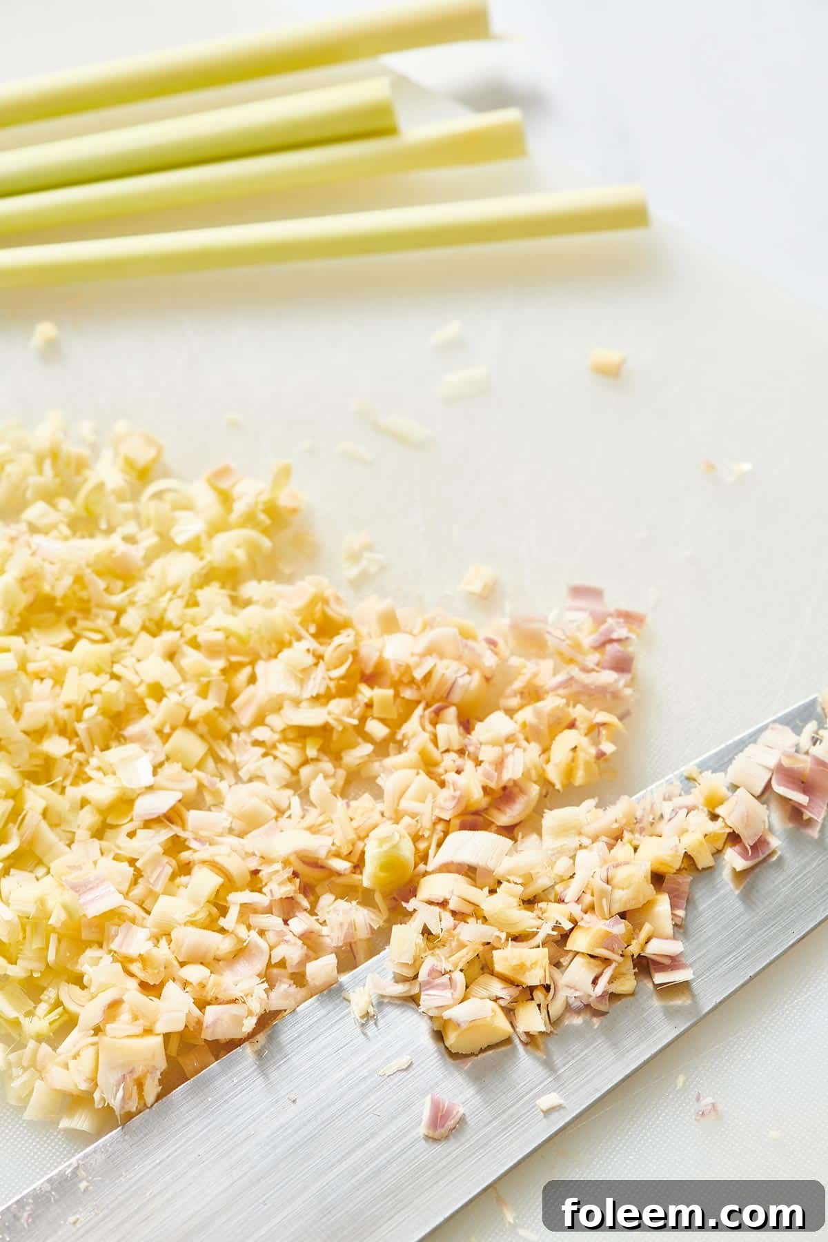 Diced fresh lemongrass on cutting board with knife.