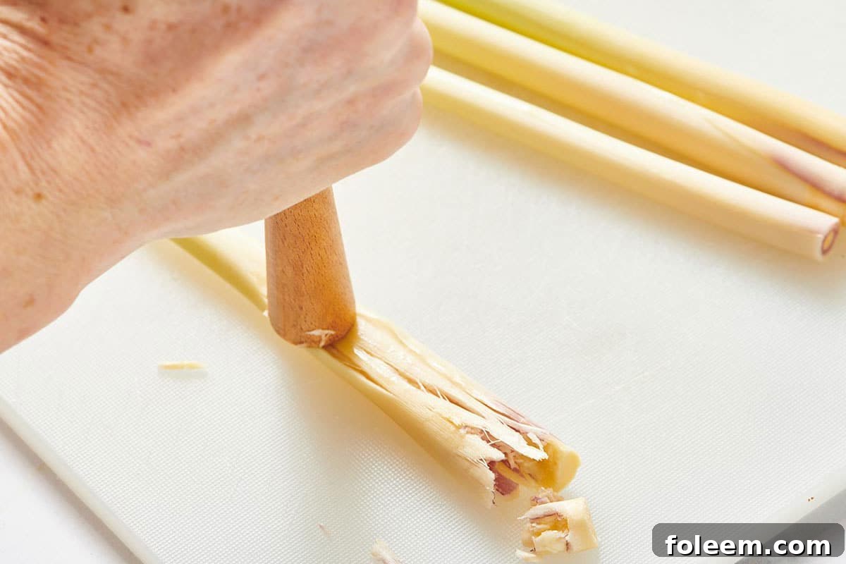 Smashing fresh lemongrass with wood mallet.
