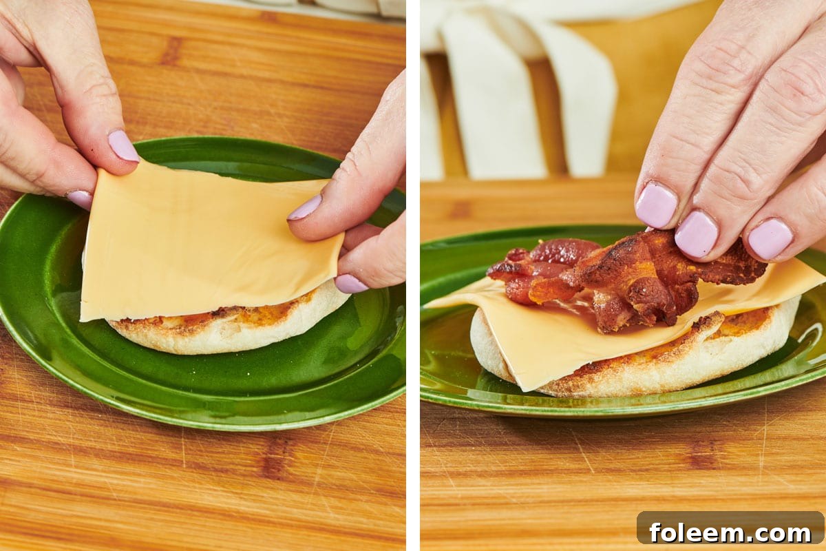 Woman topping toasted English muffin with cheese and bacon for breakfast sandwich.