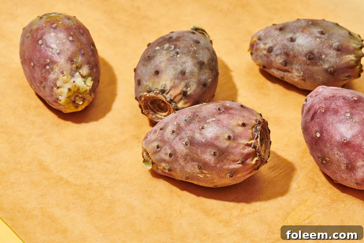Whole fresh cactus pears on wood cutting board.