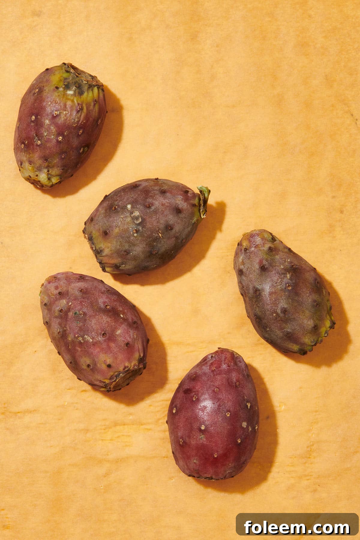 Five fresh prickly pears on cutting board.