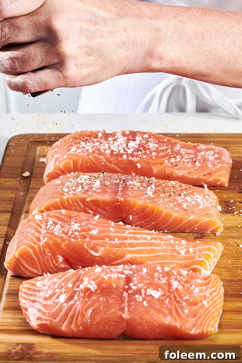 Sprinkling salt on raw salmon filets.