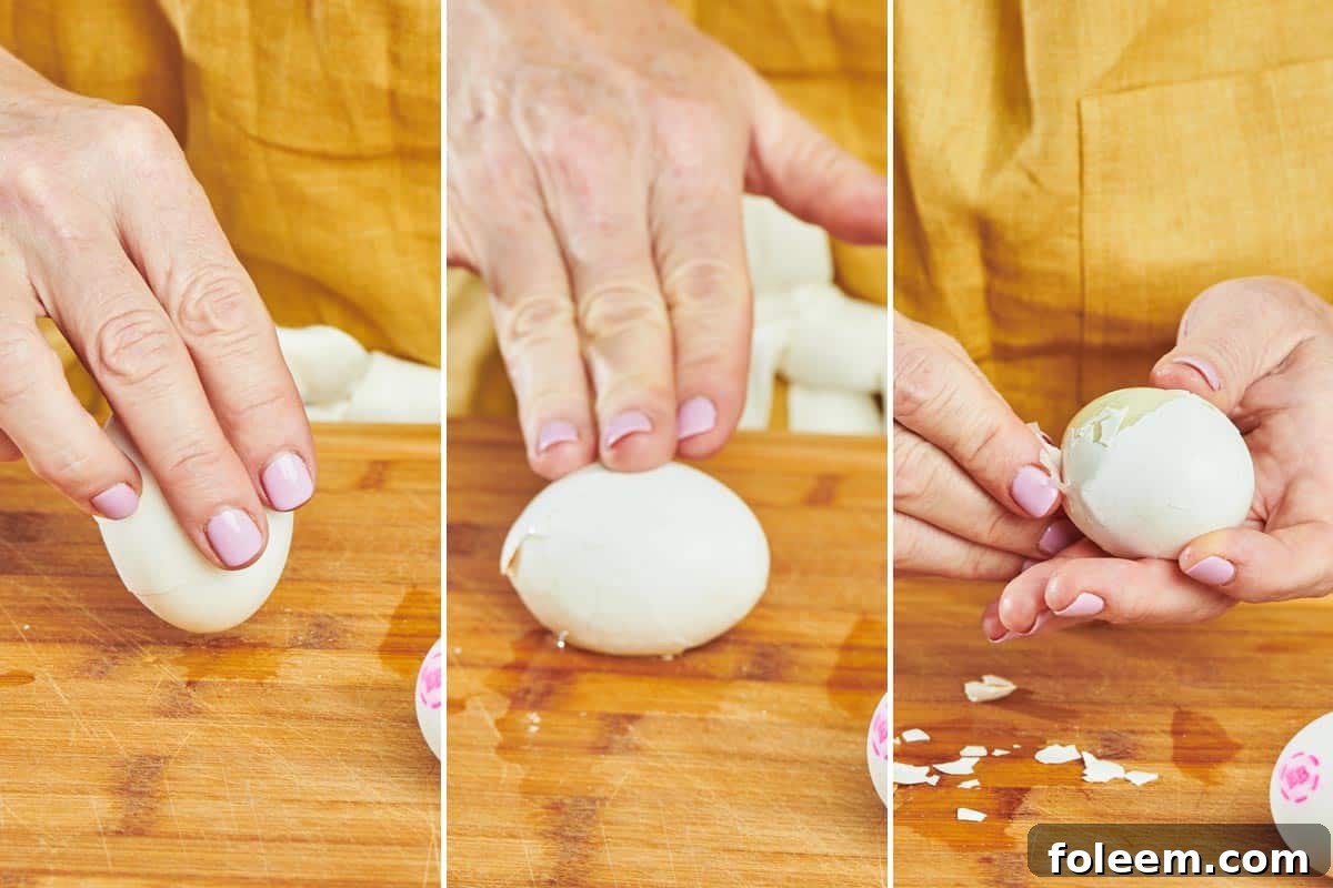 Woman peeling hard-cooked egg on wood cutting board.