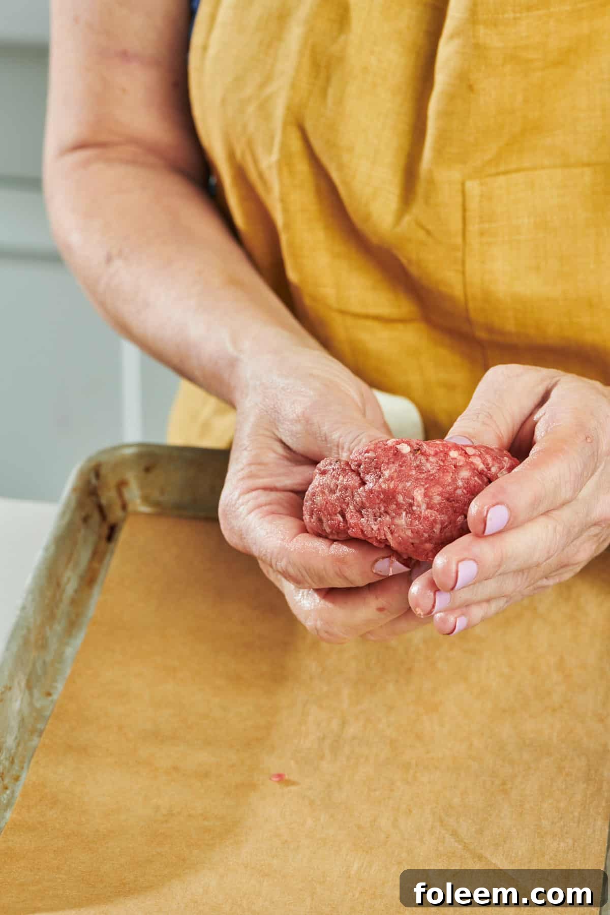 Woman forming hamburger patty from ground beef.