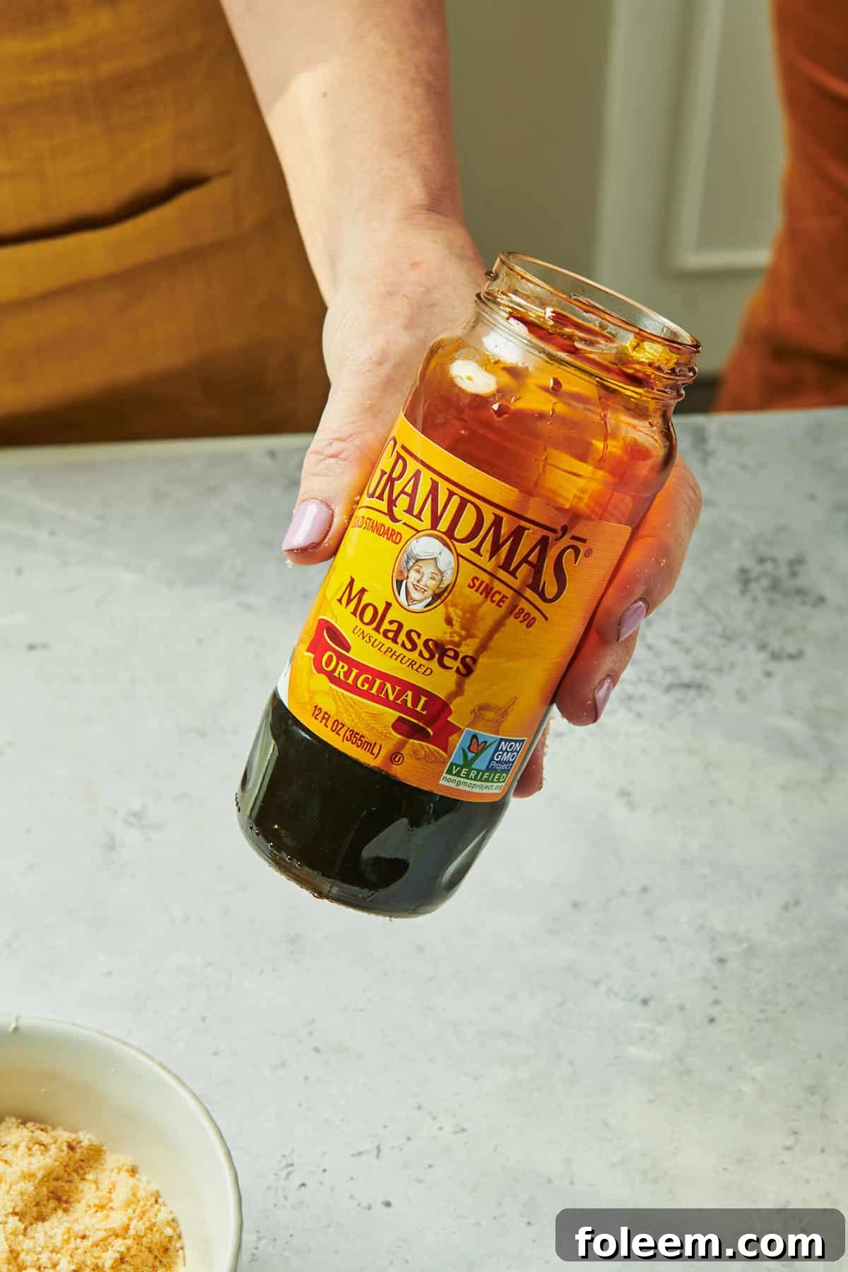 Woman holding jar of molasses.