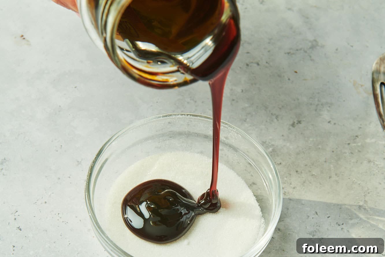 Pouring molasses from jar into bowl of white sugar.