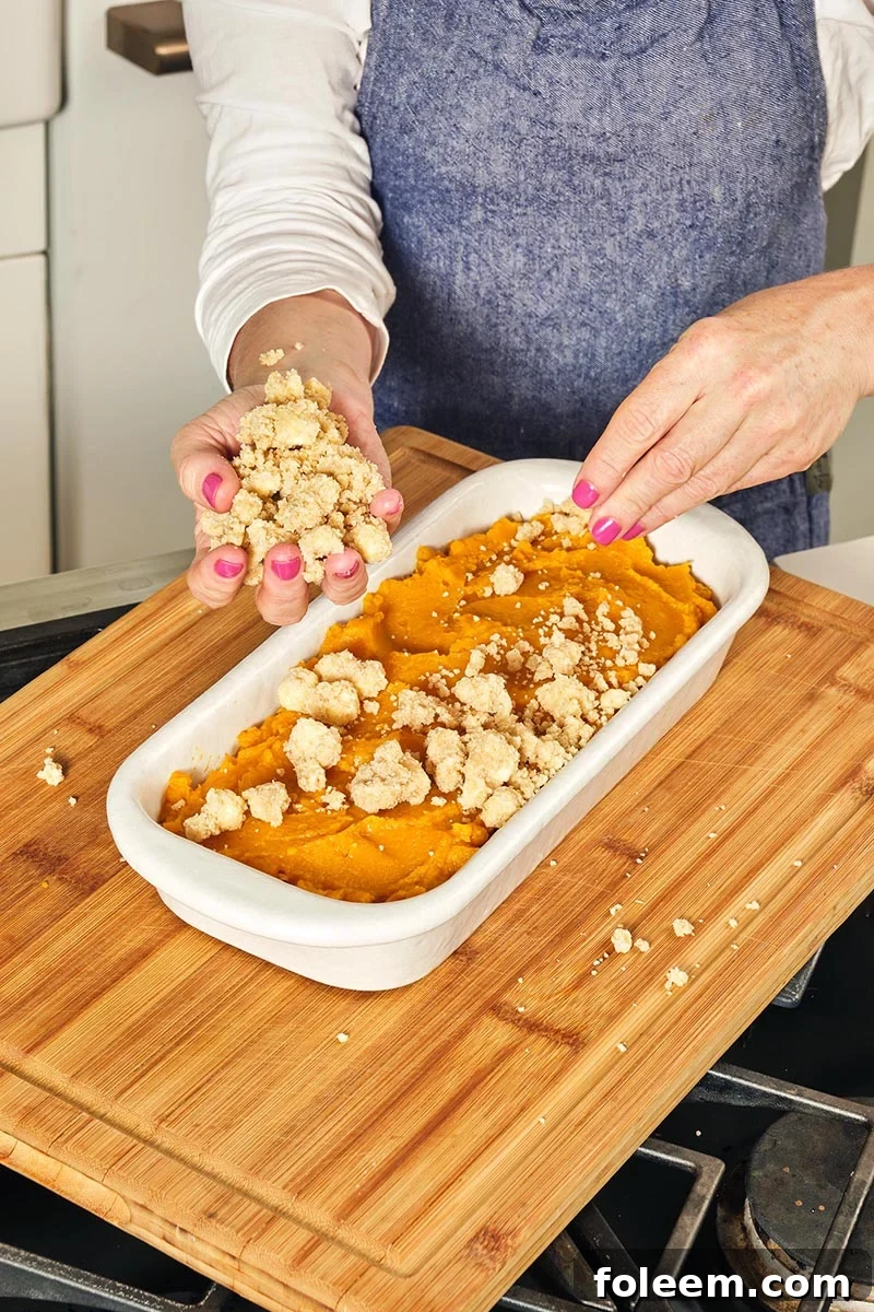 Adding topping to Butternut Squash Casserole in pan.