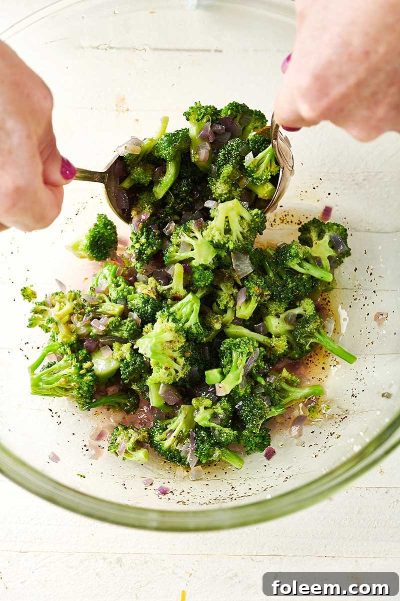 Tossing Broccoli Orzo Salad with spoons.